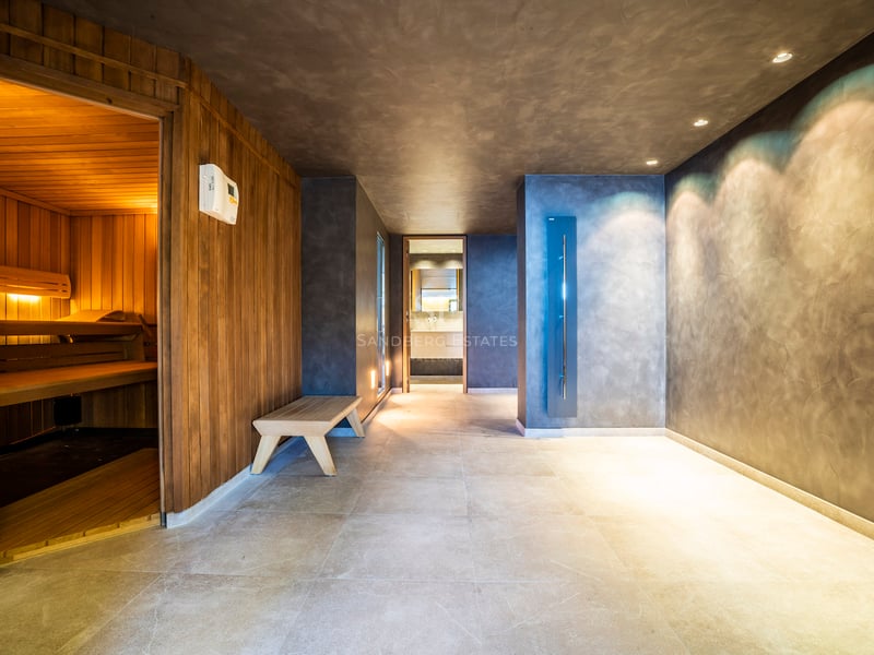 Moderner Indoor-Spa mit Holzsauna, grauen Mikrozementwänden und großformatigen Bodenfliesen.