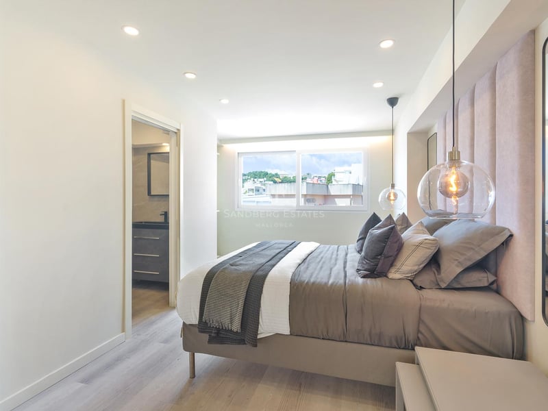 Modernes Schlafzimmer mit rosa Samtkopfteil, Glaspendelleuchten und Zugang zum En-Suite-Badezimmer.