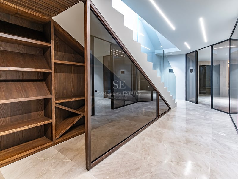 Intérieur moderne avec cave à vin en noyer, sol en marbre poli, parois vitrées et escalier avec éclairage LED.