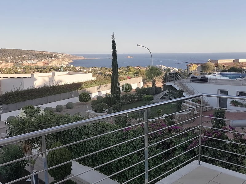 Vue surélevée depuis une terrasse avec garde-corps en acier sur la Méditerranée et les collines côtières.