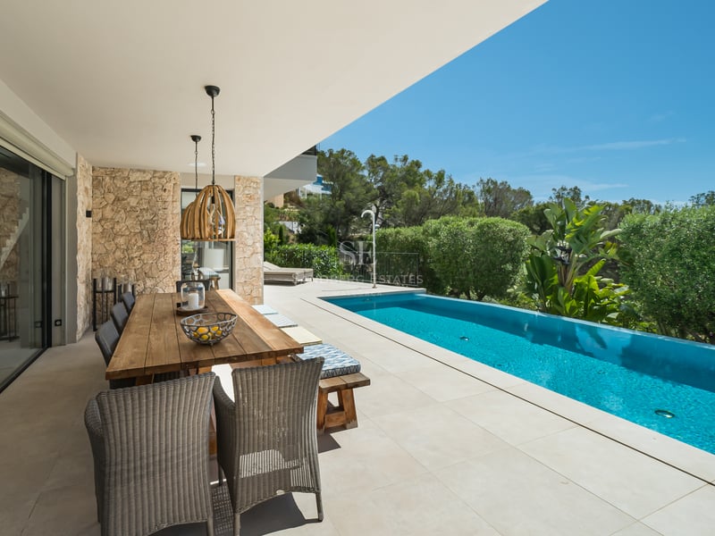Grand balcon avec vue panoramique sur la mer. Mobilier moderne, garde-corps en verre et plancher en bois. Design élégant et lumineux.