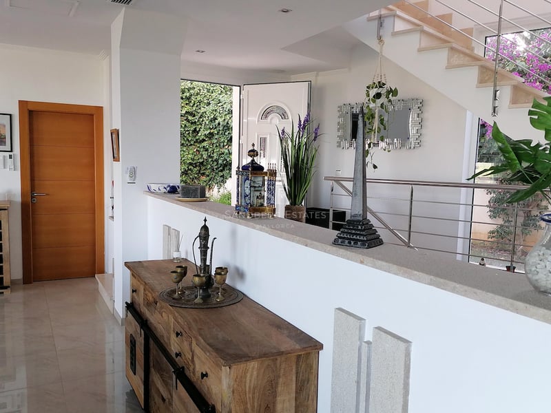 Entrée de villa spacieuse avec sols en marbre poli, buffet en bois et escalier moderne en acier inoxydable.