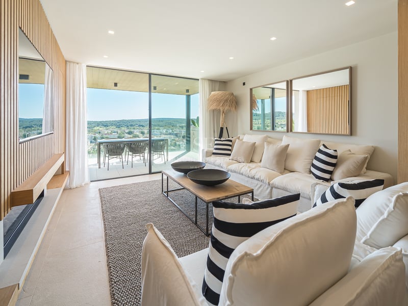 Salon moderne avec canapé blanc, mur en lattes de bois et baies vitrées s'ouvrant sur une terrasse.