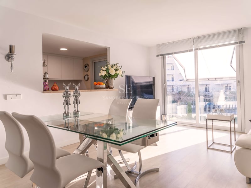 Zeitgenössischer Essbereich mit Glastisch, weißen Lederstühlen und großen Schiebetüren zur Terrasse.