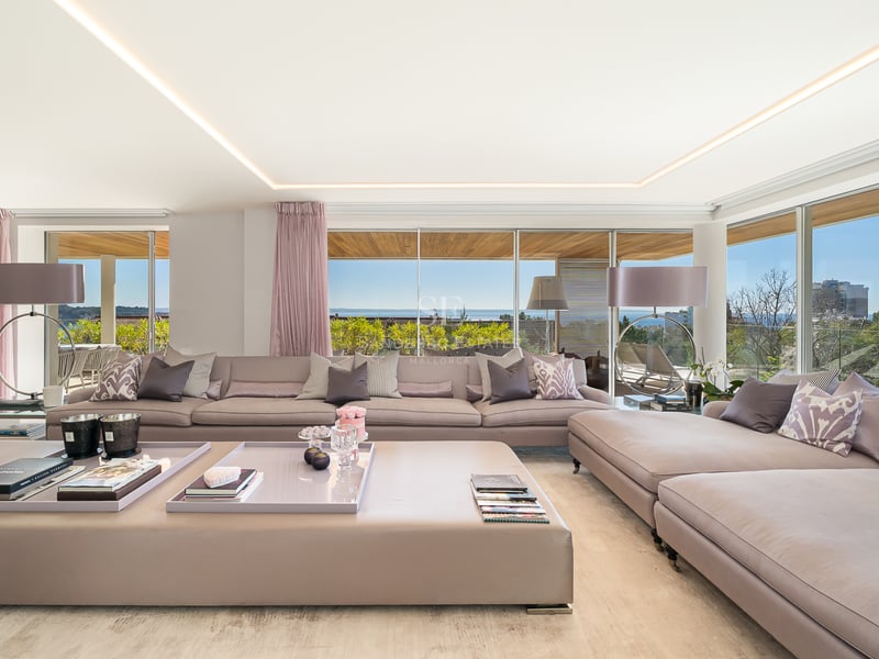 Modernes Wohnzimmer mit großer Polstergruppe und bodentiefen Verglasungen mit Meerblick.