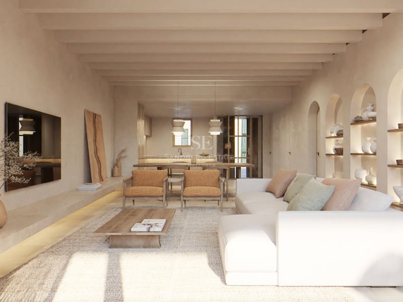 Salon lumineux avec canapé blanc, poutres en bois au plafond et niches murales cintrées exposant des céramiques.