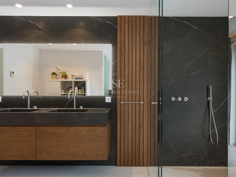 Salle de bains moderne avec double vasque en marbre noir, boiseries en noyer et douche à l'italienne vitrée.
