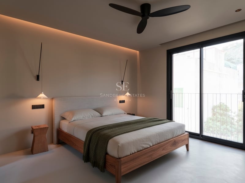 Chambre moderne avec lit en bois, suspensions design et porte vitrée coulissante ouvrant sur un balcon.