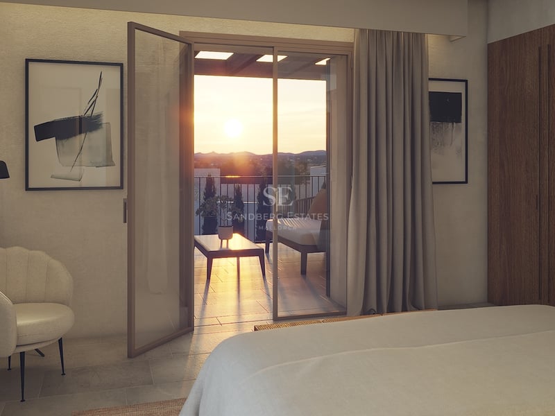 Chambre contemporaine avec baies vitrées ouvrant sur une terrasse surplombant une vallée au coucher du soleil.