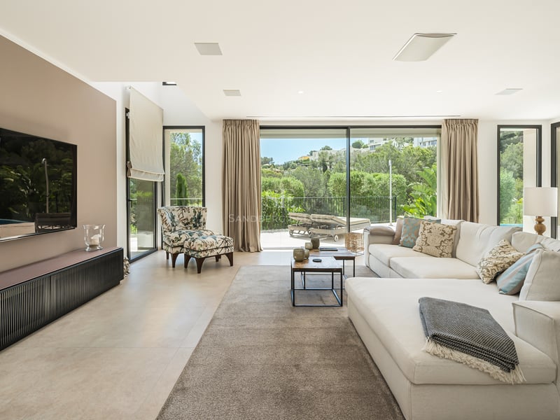 Vaste salon avec baies vitrées, parquet clair et mobilier design minimaliste. Vue sur piscine et jardin luxuriant.