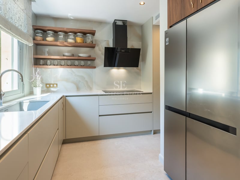 Contemporary kitchen featuring white countertops, walnut shelving, marble backsplash, and stainless steel appliances.