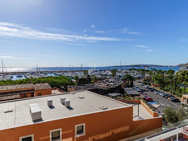 Elevated view overlooking a marina with yachts and the Mediterranean sea under a clear blue sky.