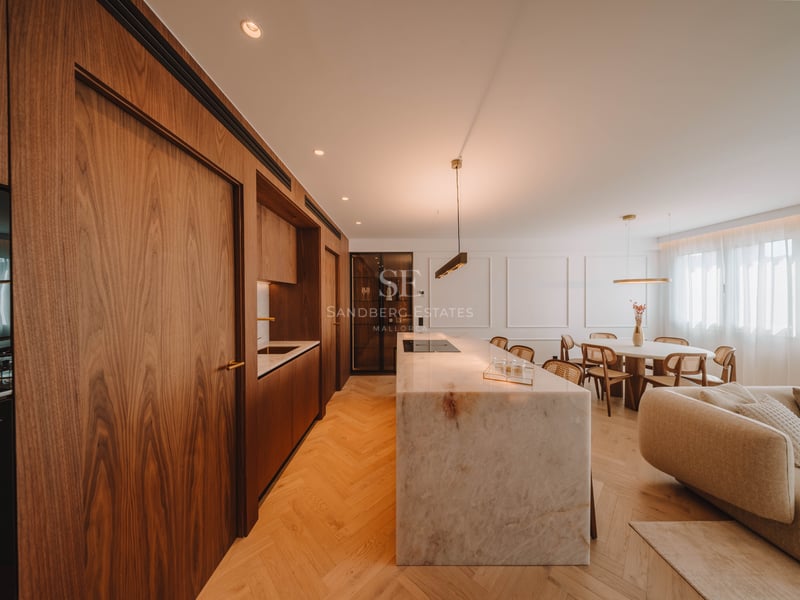 Cuisine moderne à aire ouverte avec un grand îlot en marbre, des armoires en noyer et un sol en chevrons.