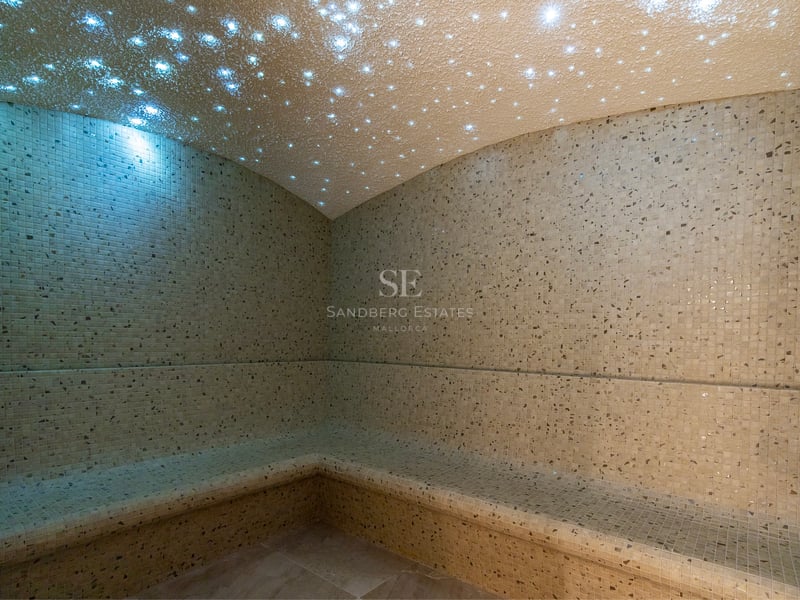 Hammam de luxe avec mosaïque beige et plafond en fibre optique effet ciel étoilé.