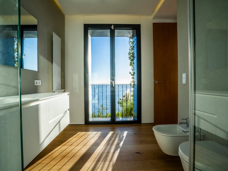 Modernes Badezimmer mit Eichenparkett und bodentiefem Fenster mit Blick auf das Mittelmeer.