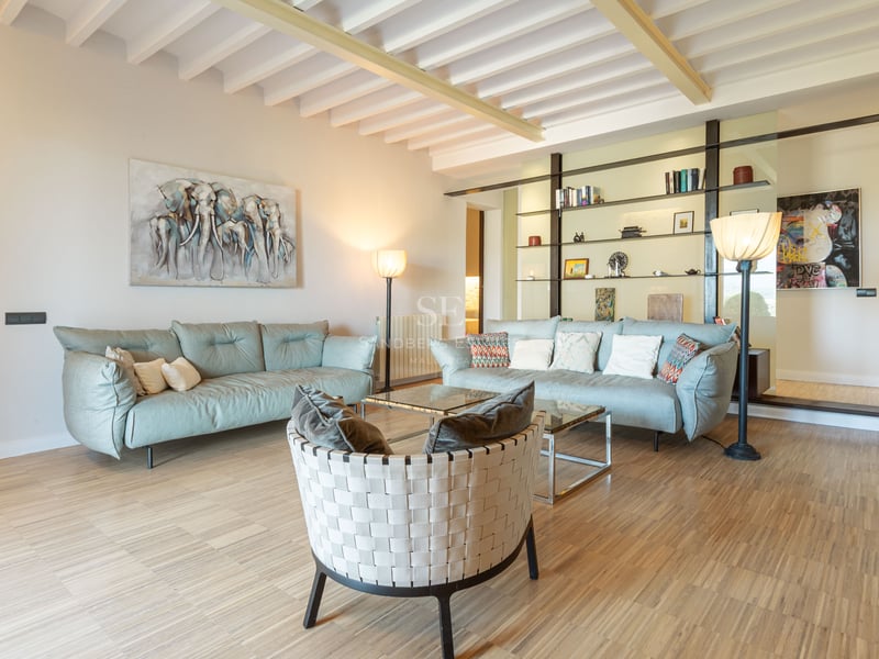 Rymligt modernt vardagsrum med ljusblå soffor, designfåtölj och vita takbjälkar.