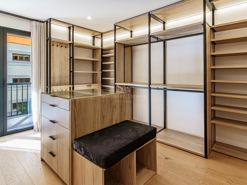 Dressing moderne avec étagères en bois clair, cadres en métal noir, un îlot central et accès au balcon.