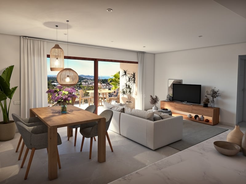 Bright open-concept living and dining area with wooden furniture and large windows overlooking a scenic coastline.