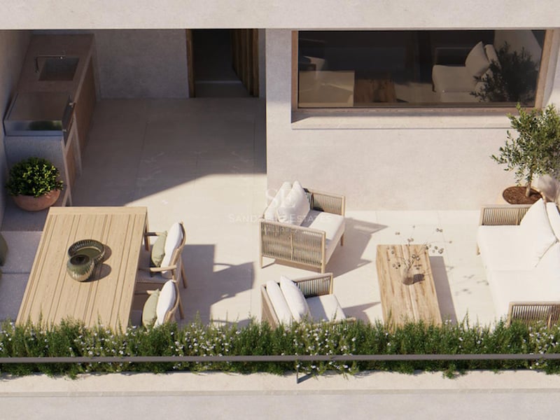 Vue plongeante d'une terrasse moderne ensoleillée comprenant un salon, une table à manger et une cuisine d'été avec grill.