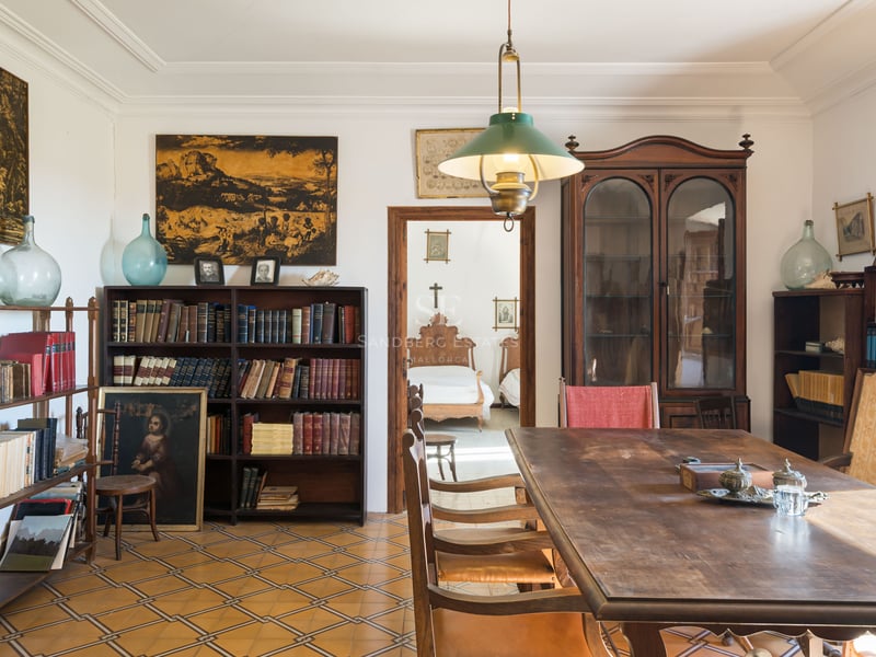 Pièce classique avec une grande table en bois, des étagères de livres et un sol en carreaux décorés.