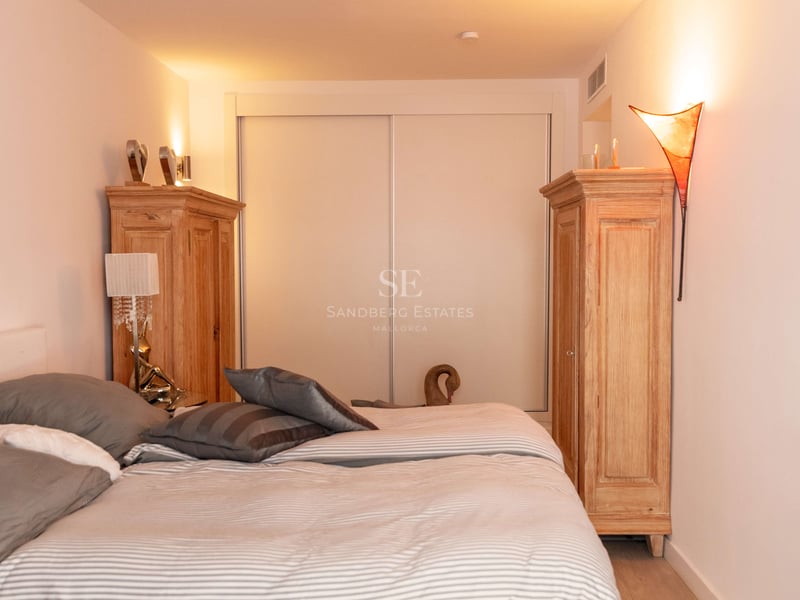 Helles Schlafzimmer mit großem Bett, zwei Holzschränken und Einbauschiebetüren bei warmer Ambientebeleuchtung.