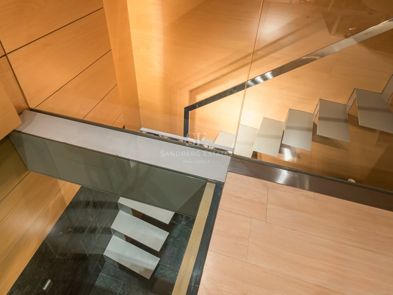Vue plongeante d'un escalier moderne avec marches en verre et parois en bois chaleureux.