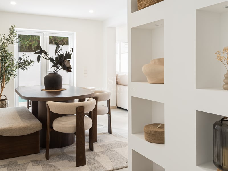 Salle à manger contemporaine avec table en bois sombre, chaises crème et niches murales décoratives blanches.