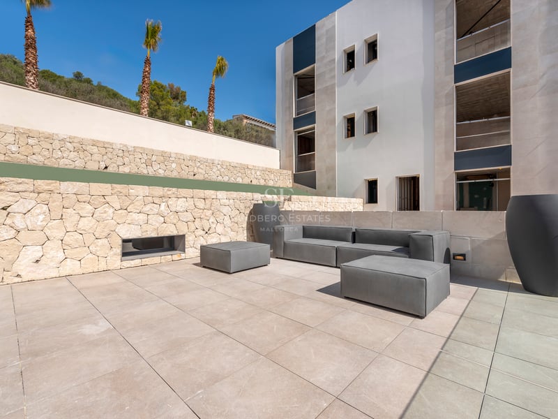 Salon extérieur contemporain avec canapés gris sur une terrasse en pierre à côté d'un mur en pierre naturelle.
