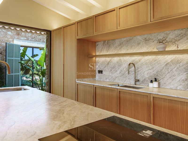 Moderne Küche mit hellen Holzschränken, Marmorrückwand und Kochinsel mit Induktionskochfeld.