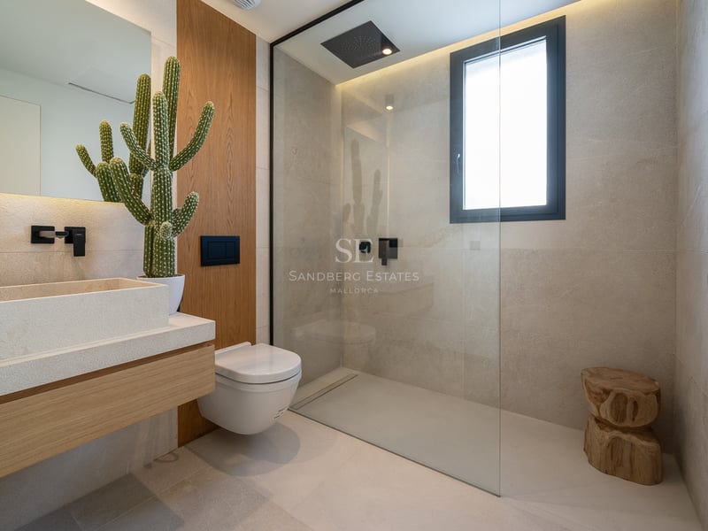 Salle de bains moderne avec douche à l'italienne, vasque en pierre et robinetterie noire mate.