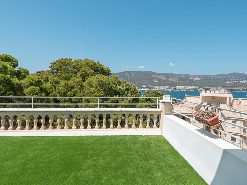 Terrasse avec gazon synthétique, balustrade en pierre et vue sur la Méditerranée et les montagnes environnantes.
