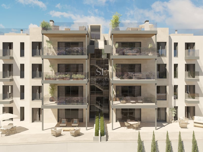 Immeuble résidentiel en pierre beige avec de grandes terrasses, garde-corps en verre et larges baies vitrées.