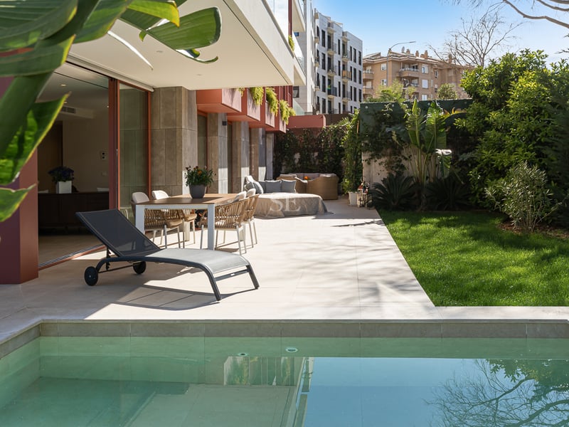 Luxury outdoor terrace featuring a private plunge pool, dining area, and manicured lawn surrounded by greenery.