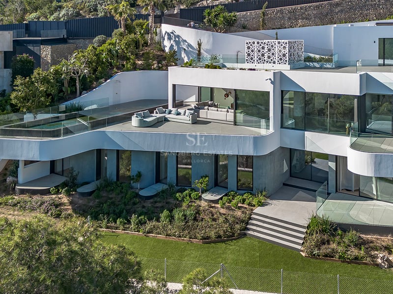 Villa blanche moderne à plusieurs niveaux avec piscine à débordement, terrasses courbes et jardins luxuriants.