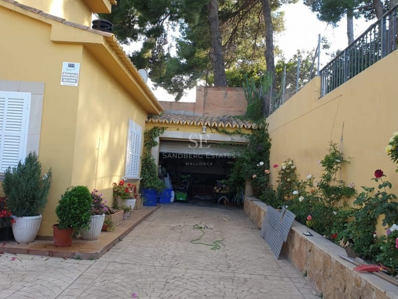 Aerial view of a luxurious villa with infinity pool, lush gardens, and modern architecture. Open spaces and large window fronts.