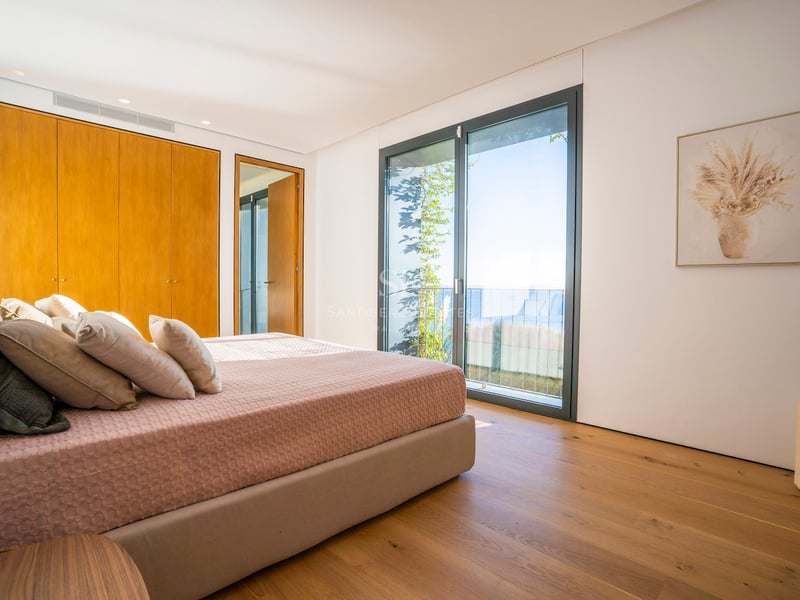 Schlafzimmer mit Eichenparkett, maßgefertigten Kleiderschränken und Schiebetüren mit Blick auf das Mittelmeer.