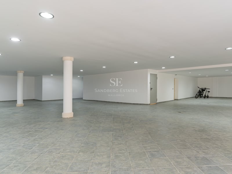 Geräumige Tiefgarage mit grauen Fliesen, weißen Wänden, LED-Einbaustrahlern und weißen Stützpfeilern.