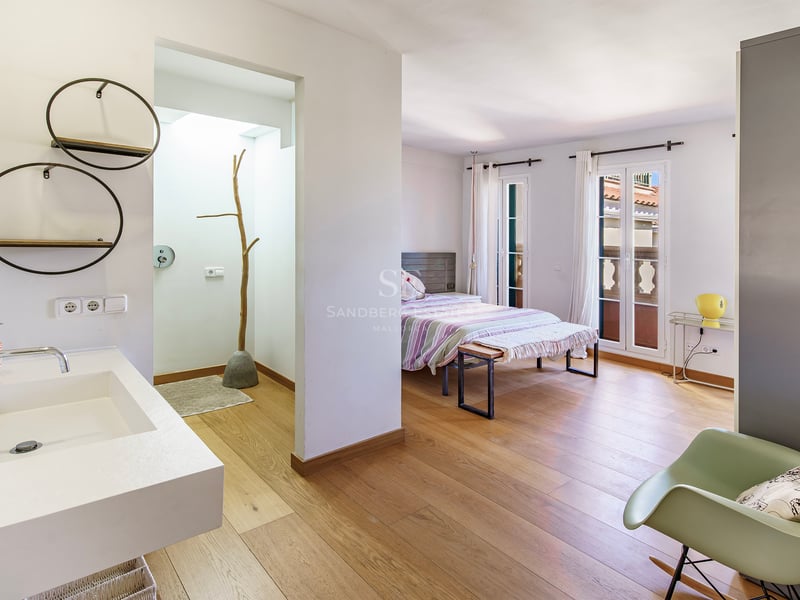 Rymligt sovrum med ljust ekparkettgolv och öppet badrum med modern vit kommod.