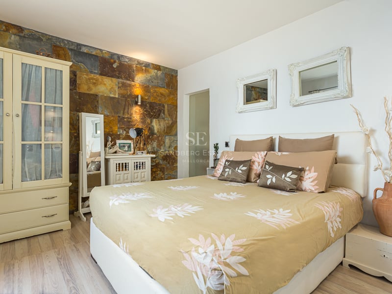 Modern view of a villa featuring an infinity pool, large windows, and minimalist design. Lush vegetation and blue sky backdrop.