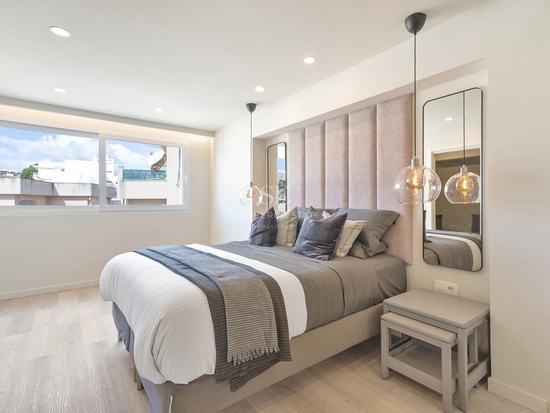 Zeitgenössisches Schlafzimmer mit gepolstertem Kopfteil, Glaspendelleuchten und hellem Holzboden.