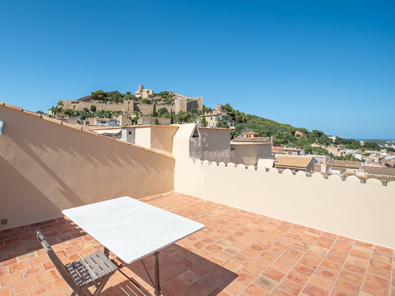 Terrasse sur le toit avec carrelage en terre cuite surplombant un château historique sur une colline verdoyante.