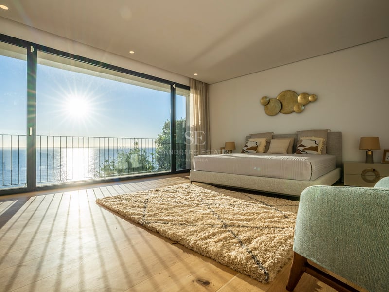 Helles Hauptschlafzimmer mit bodentiefen Glastüren, Eichenparkett und Terrasse mit Blick auf das blaue Meer.