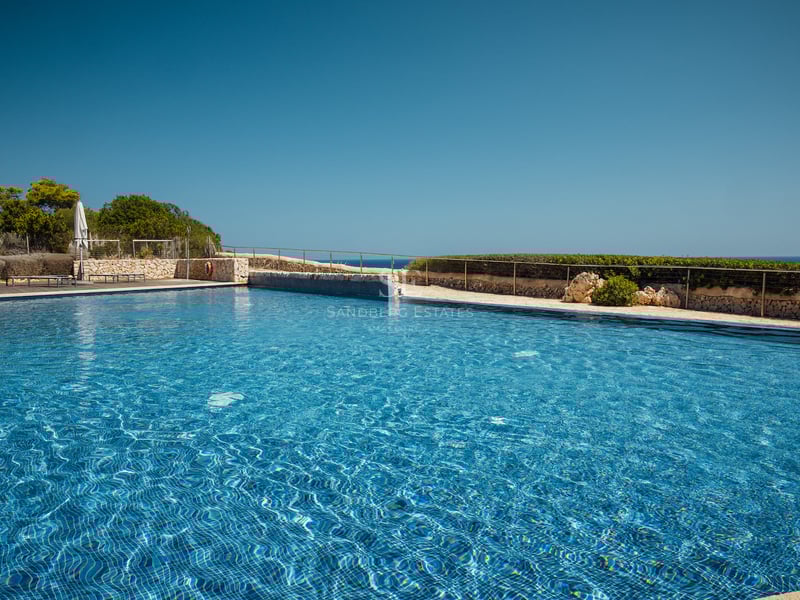 Une grande piscine carrelée en bleu entourée de murs en pierre naturelle et d'une balustrade en métal.
