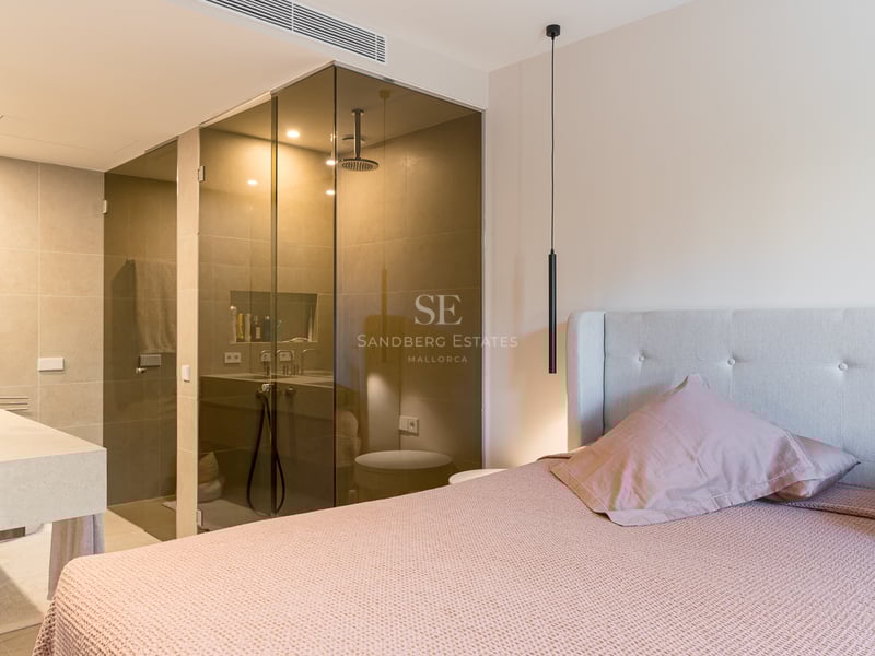 Contemporary master bedroom featuring a glass-enclosed shower, stone vanity, and dusty pink bedding.