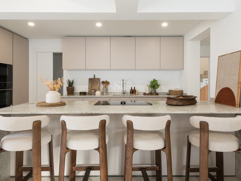 Cuisine moderne avec des placards beiges, un grand îlot en pierre et quatre taburetes en bois et tissu.