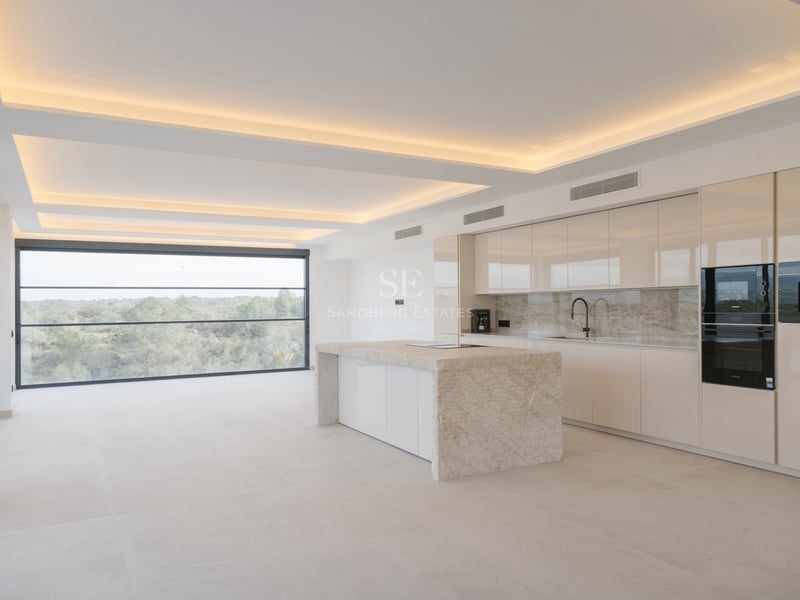 Moderne Küche mit Natursteininsel, Hochglanzschränken und bodentiefem Panoramafenster mit Blick ins Grüne.