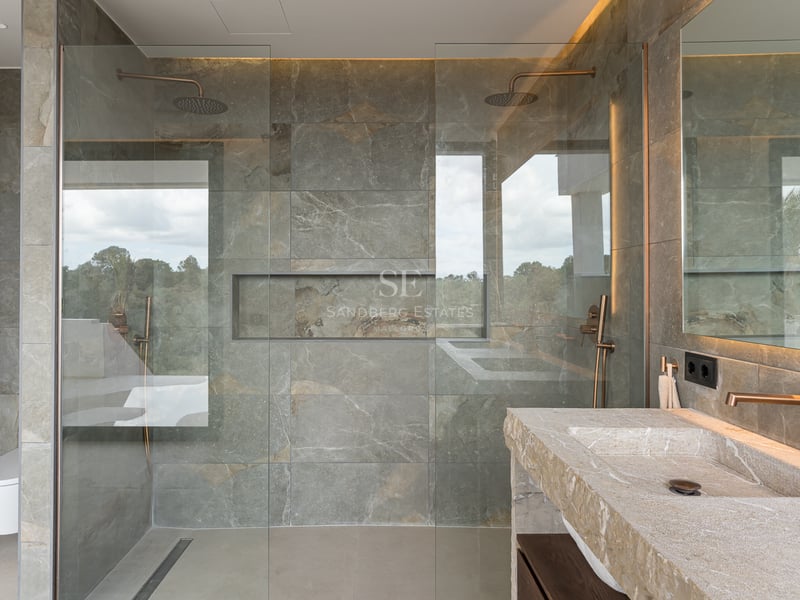 Zeitgenössisches Badezimmer mit grauen Steinfliesen, Glasduschwand und Waschtisch aus Naturstein.