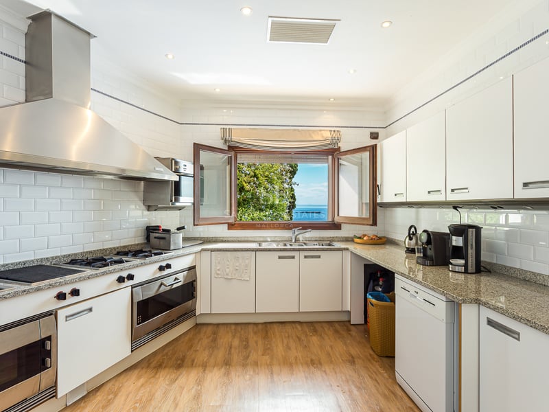 Extérieur d'une villa moderne avec piscine à débordement, grandes terrasses, design minimaliste et vues panoramiques. Façade blanche et végétation luxuriante.