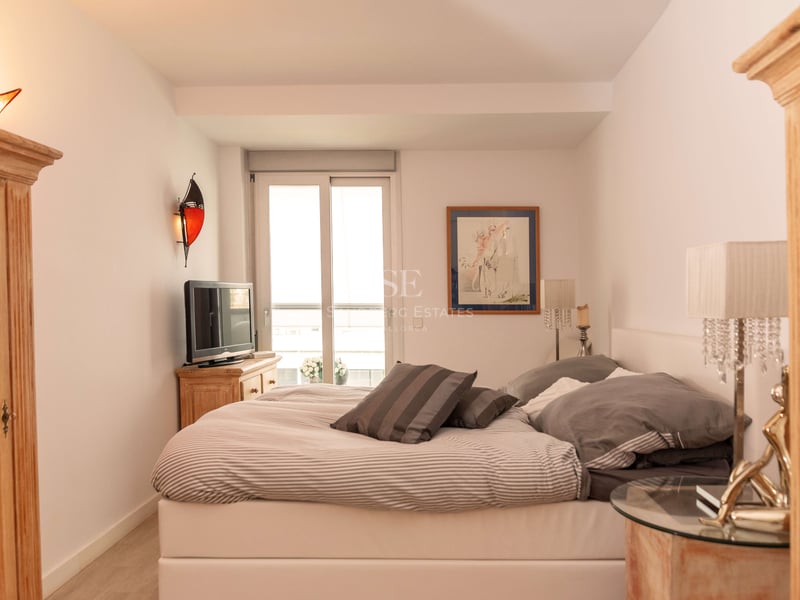 Ein Schlafzimmer mit großem Bett, Pinienholzmöbeln, Kristalllampen und Glasschiebetür zum Balkon.