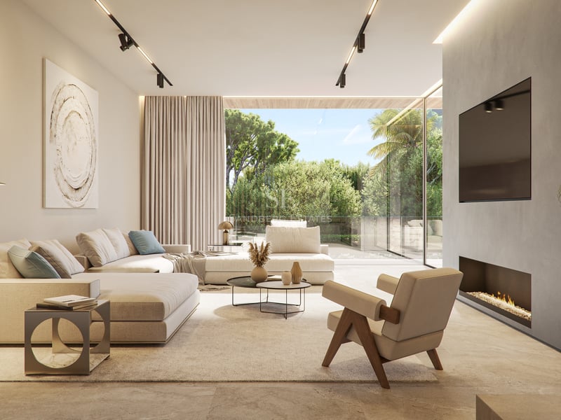 Modern living room with neutral sofas, designer chair, and floor-to-ceiling glass doors leading to a green terrace.